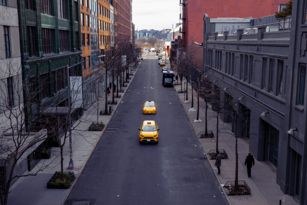 A quiet street in Chelsea New york, with just two yellow taxis driving down the centre of the road